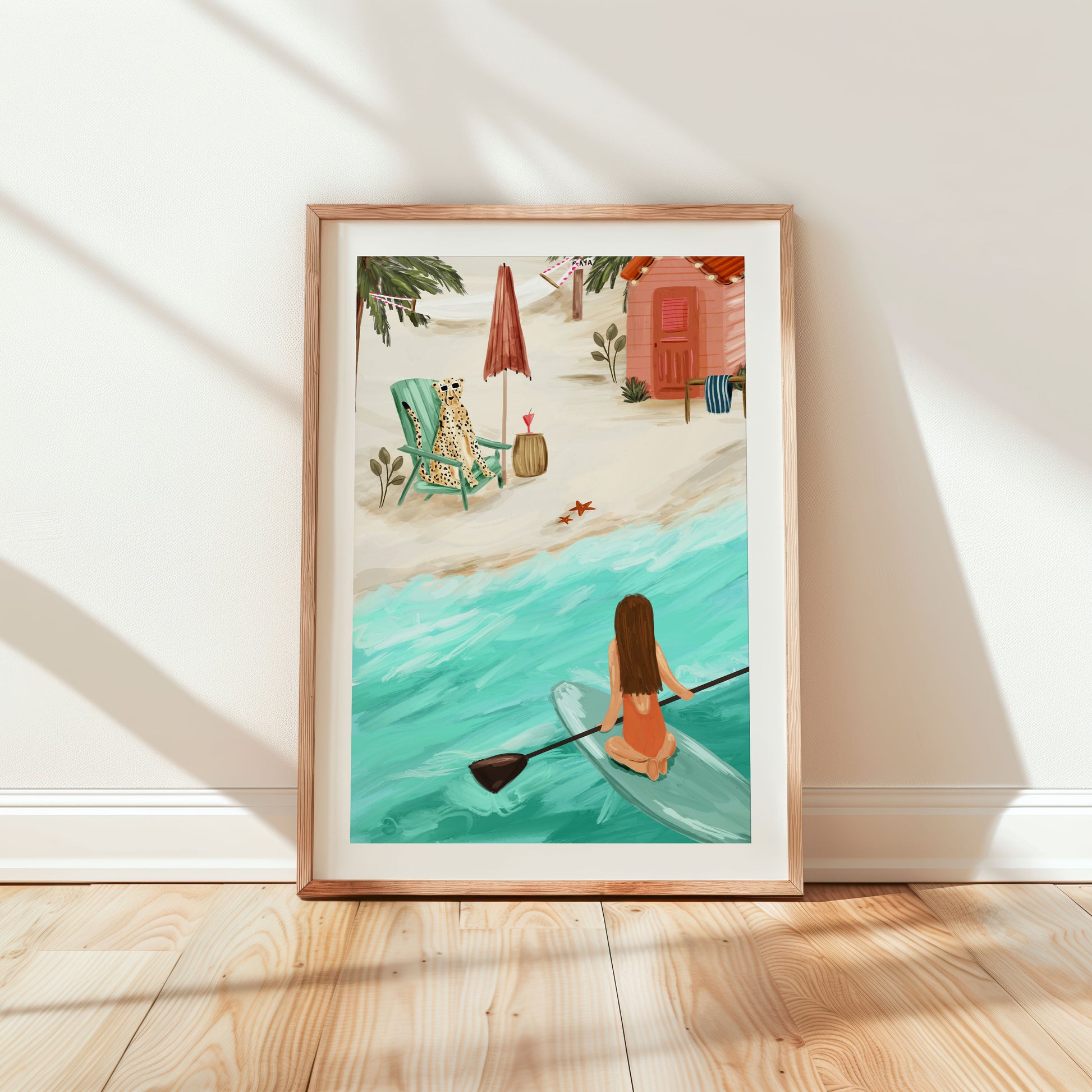 Coastal beach scene whimsical art print, featuring a girl paddle boarding in the sea overlooking a cheetah chilling in the sun on a deck chair.