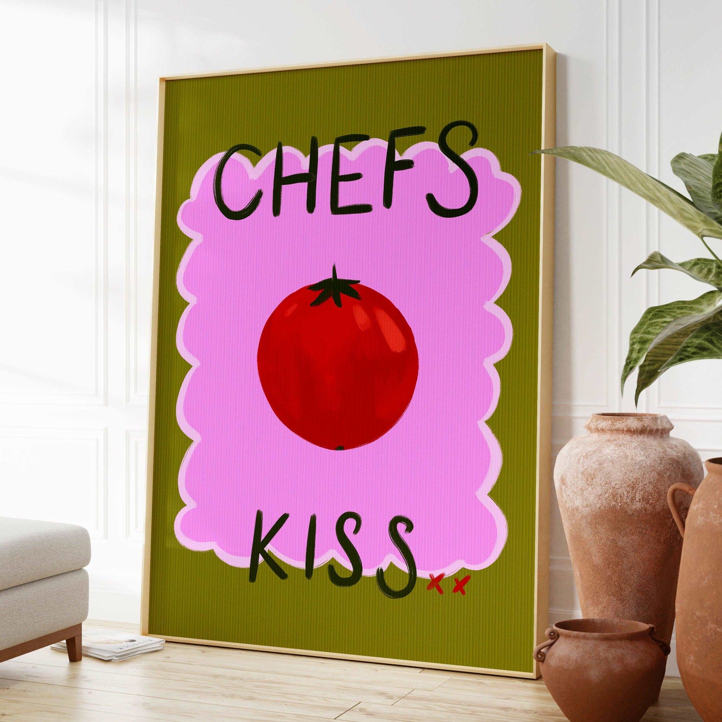 Bright kitchen nook wall art print featuring a painted red tomato with "chefs kiss" handwritten. On a green and pink textured background.