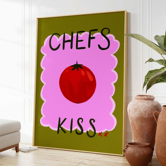 Bright kitchen nook wall art print featuring a painted red tomato with "chefs kiss" handwritten. On a green and pink textured background.