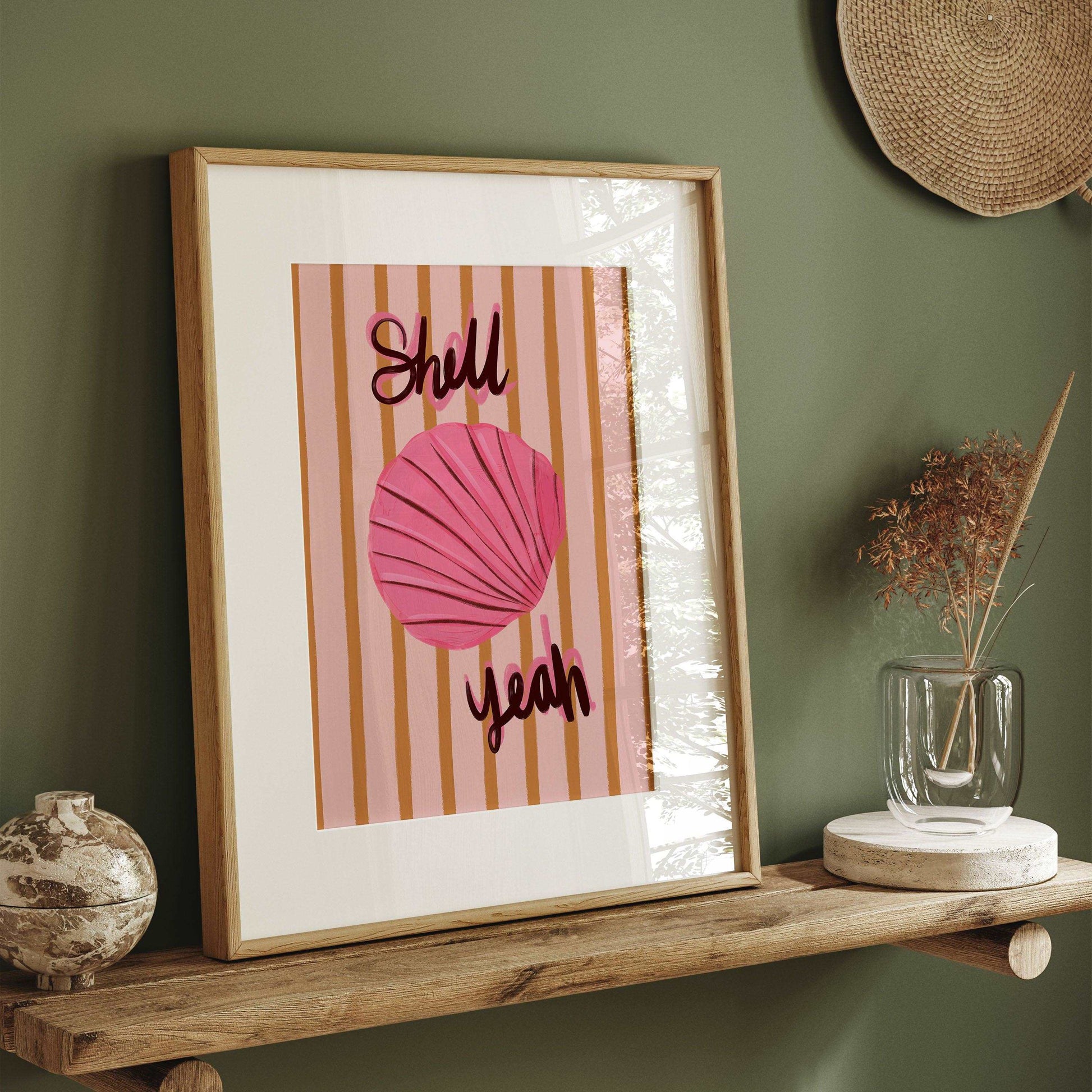 Painterly pink seashell art print with bold handwritten text "Shell Yeah". On a mustard yellow and pink striped background