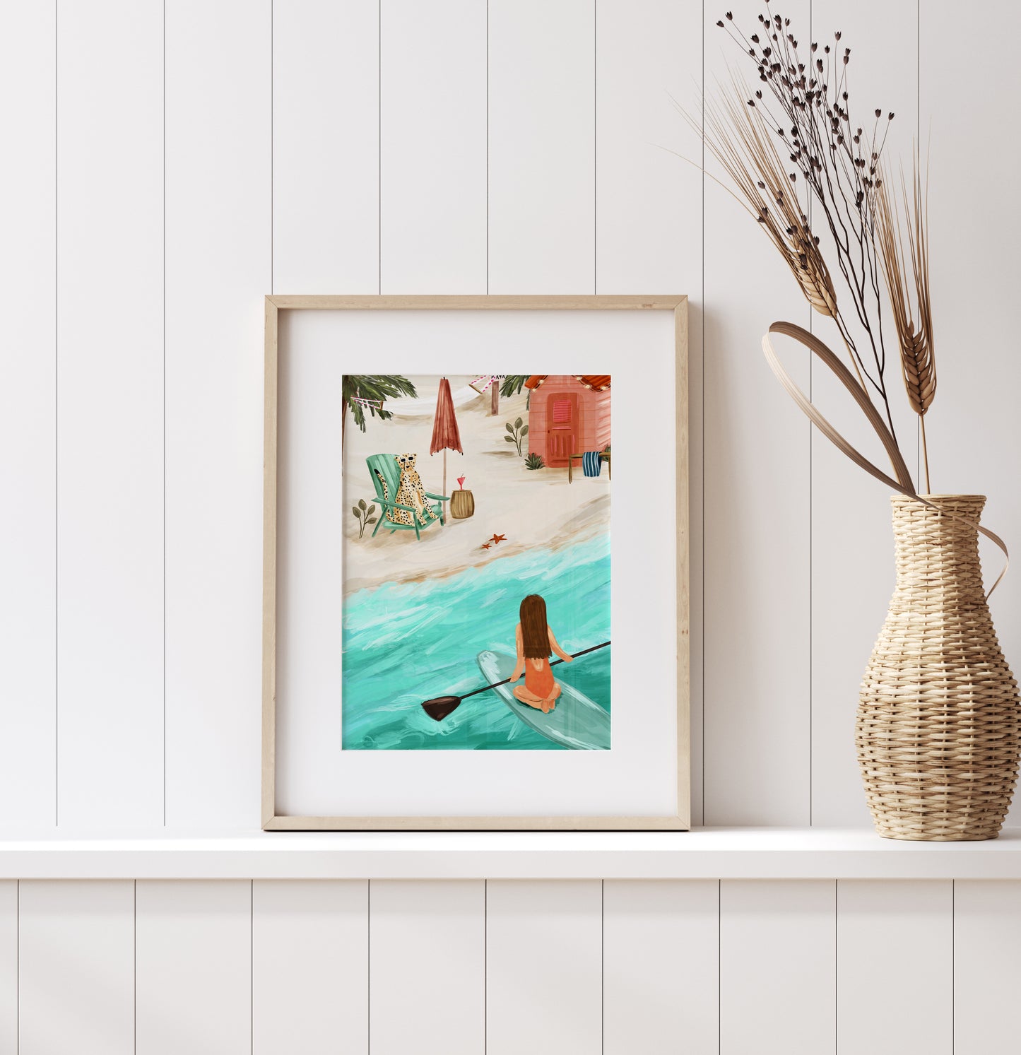 Coastal beach scene whimsical art print, featuring a girl paddle boarding in the sea overlooking a cheetah chilling in the sun on a deck chair.